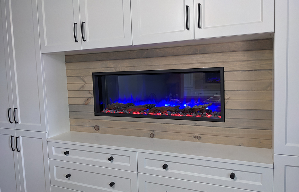 Modern linear gas fireplace built into white cabinetry with wood plank surround